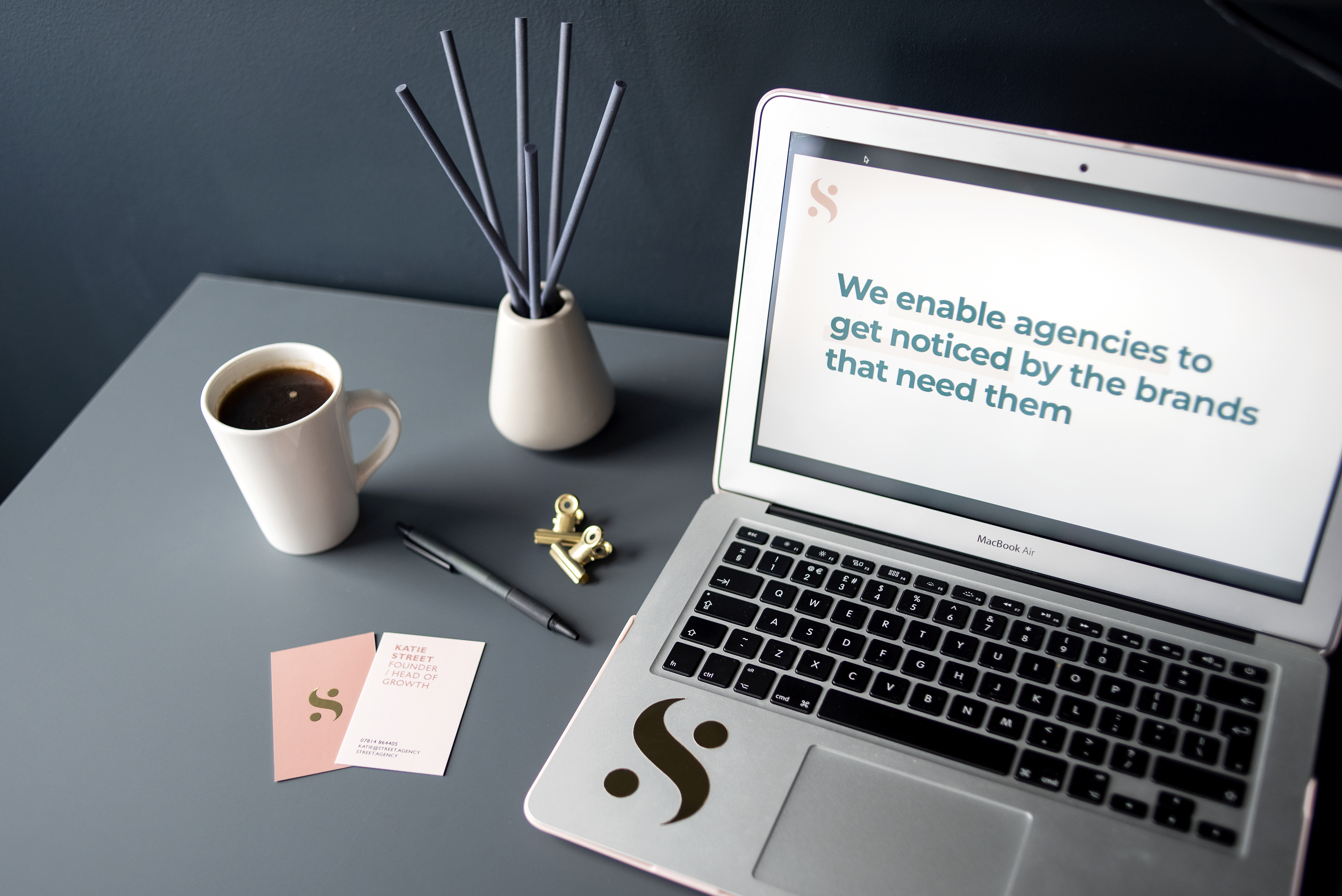 A table with a cup of coffee, laptop and business cards 